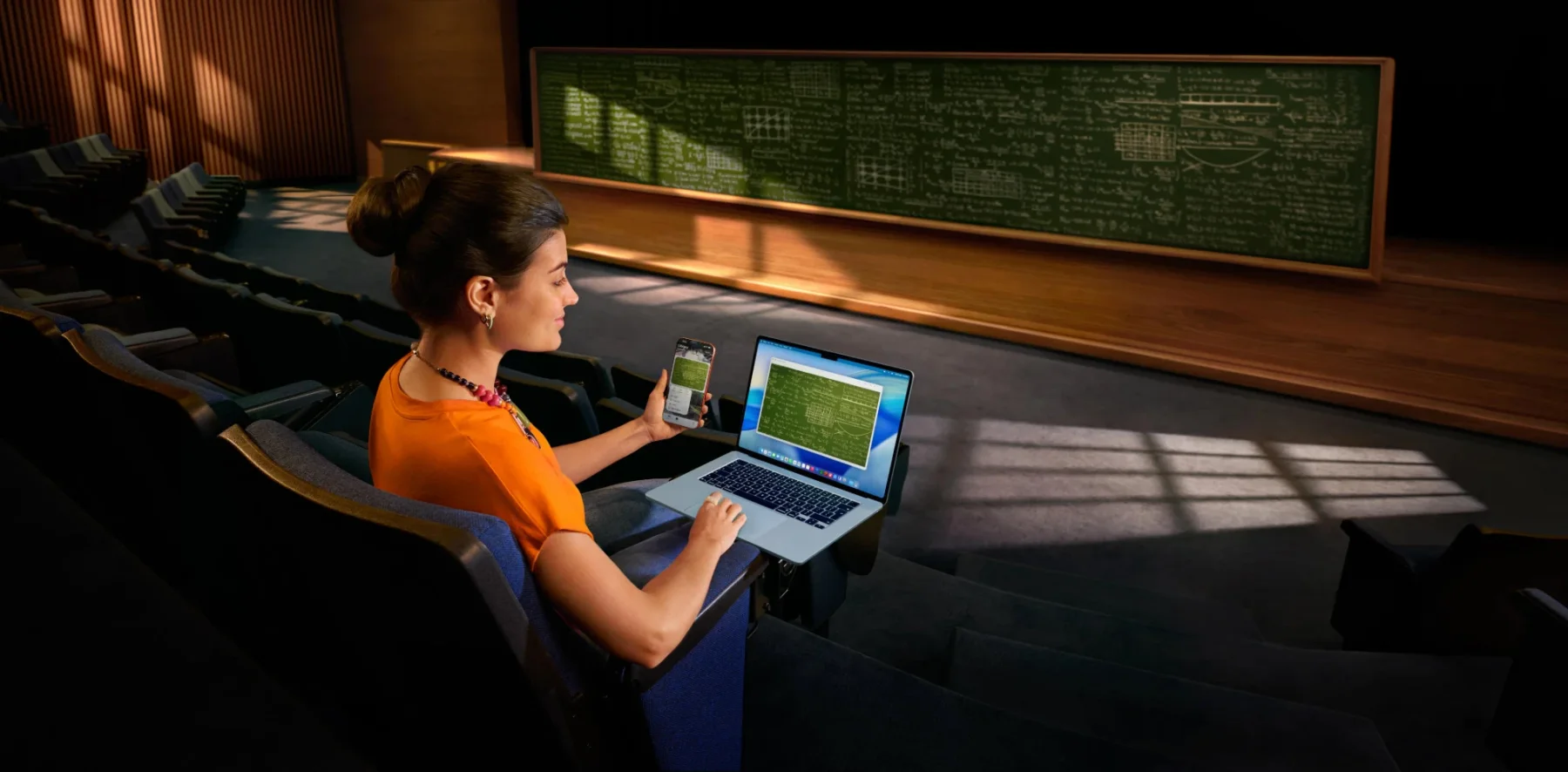 Étudiante travaillant sur un MacBook Air et un iPhone dans un amphithéâtre